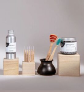 discovery pack of georganics - toothbrush, tongue brush, toothpaste, oil pulling and interdental brushes on grey background by veganlyy