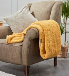 vegan happy yellow vegan ribbon teddy bear throw blanquet on brown chair presented by veganlyy.com
