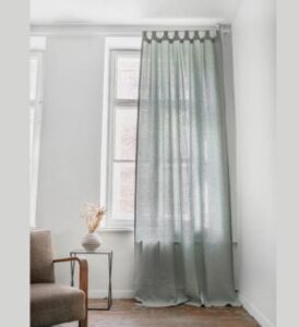 a window covered with sage green amourlinen tab top linen curtain and white walls background presented by veganlyy
