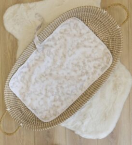 looking from above to a small basket with sustainable eco baby travel changing mat light brown stains on beige colour presented by veganlyy