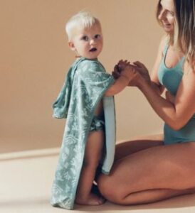 veganlyy econaps modern cloth nappies swim sea life poncho for beach or pool worn by a todler holding hands with his mother