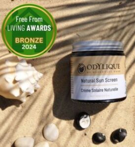 veganlyy odylique vegan natural sun screen jar laying on sand under a palm shadow